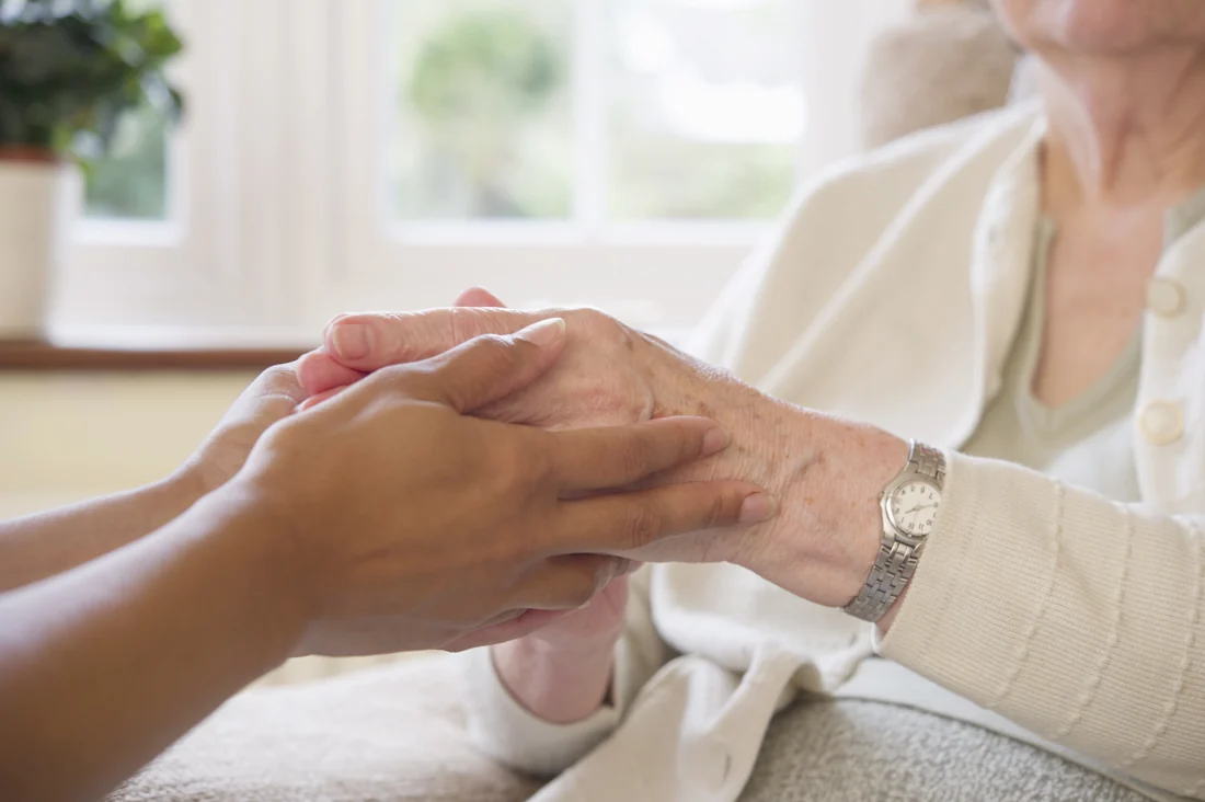 Hände einer Pflegekraft und einer älteren Person